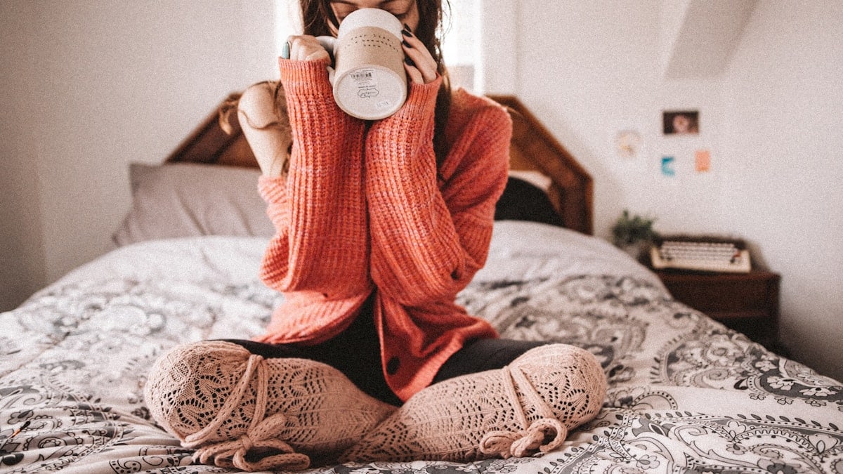 woman in red knit sweater holding white ceramic mug
