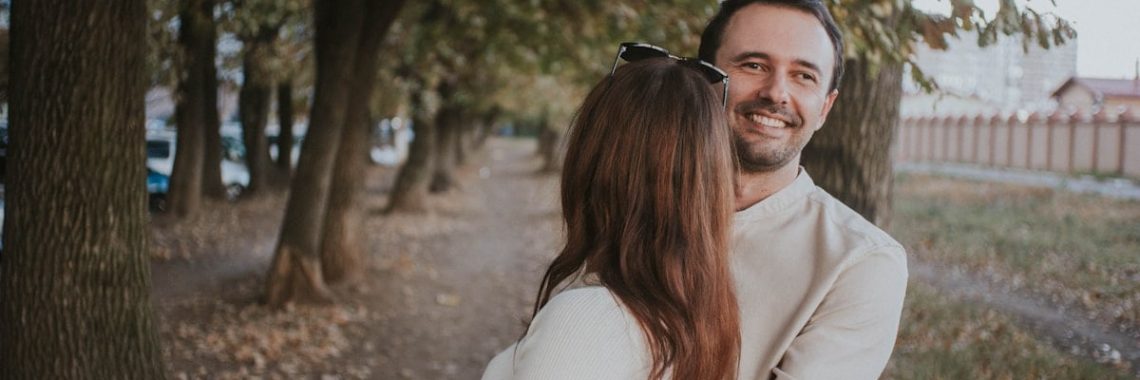 a man holding a woman in his arms in a park