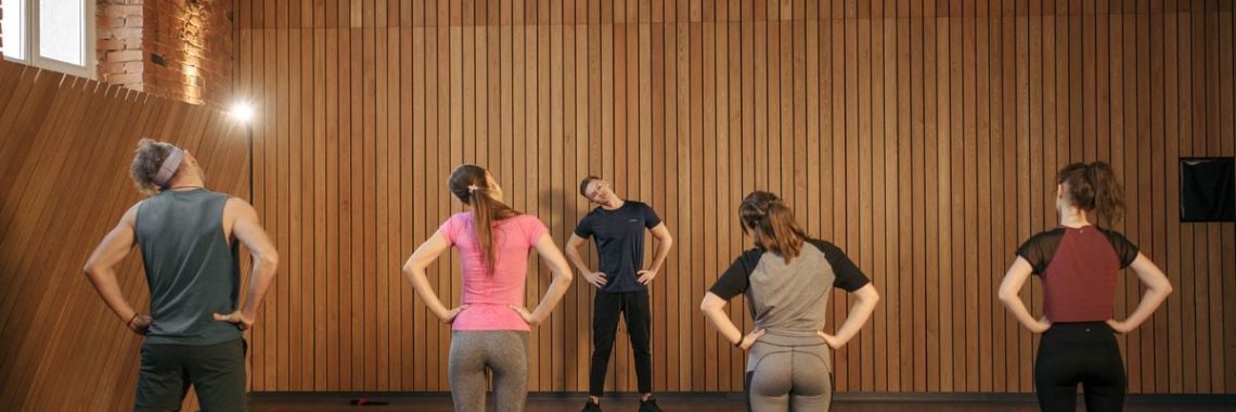 Men and women performing stretching exercises on mats in a fitness class