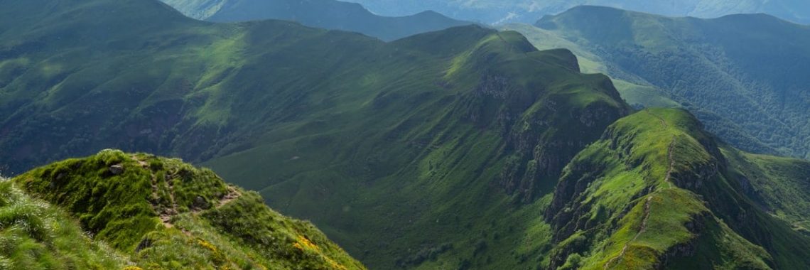 a person standing on a grassy hill with mountains in the background